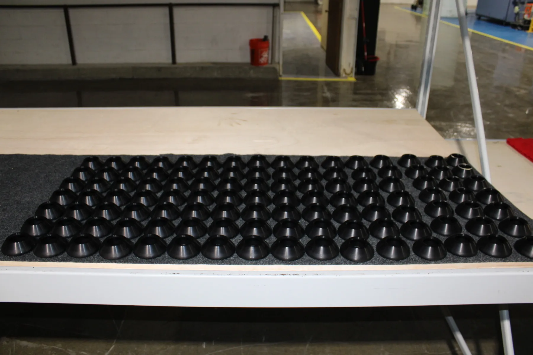 Rows of black anodized aluminum conical parts finished and laid out on the bench