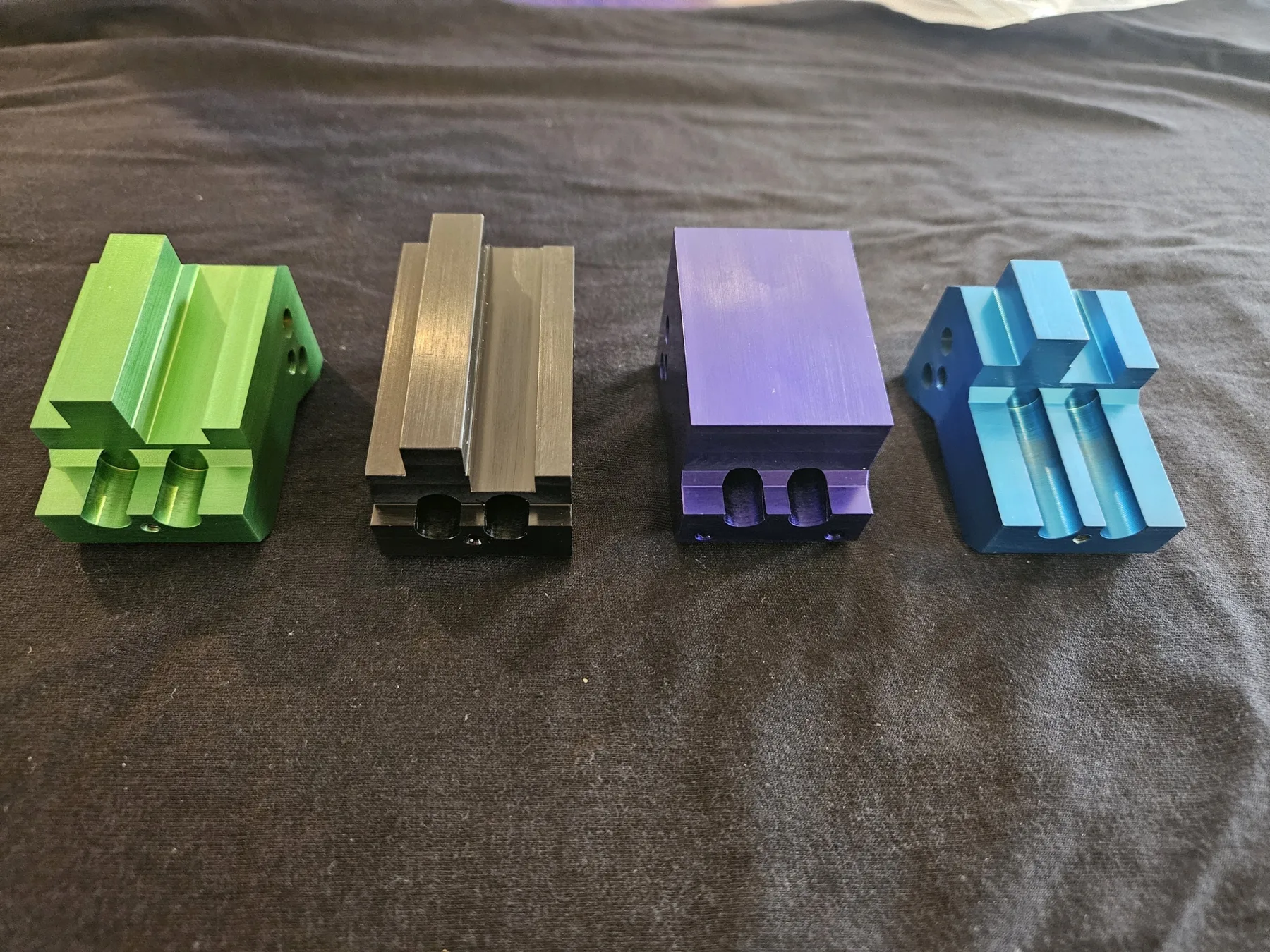 Anodized aluminum fixture blocks in green, gray, purple, and blue finished at AnoPRO