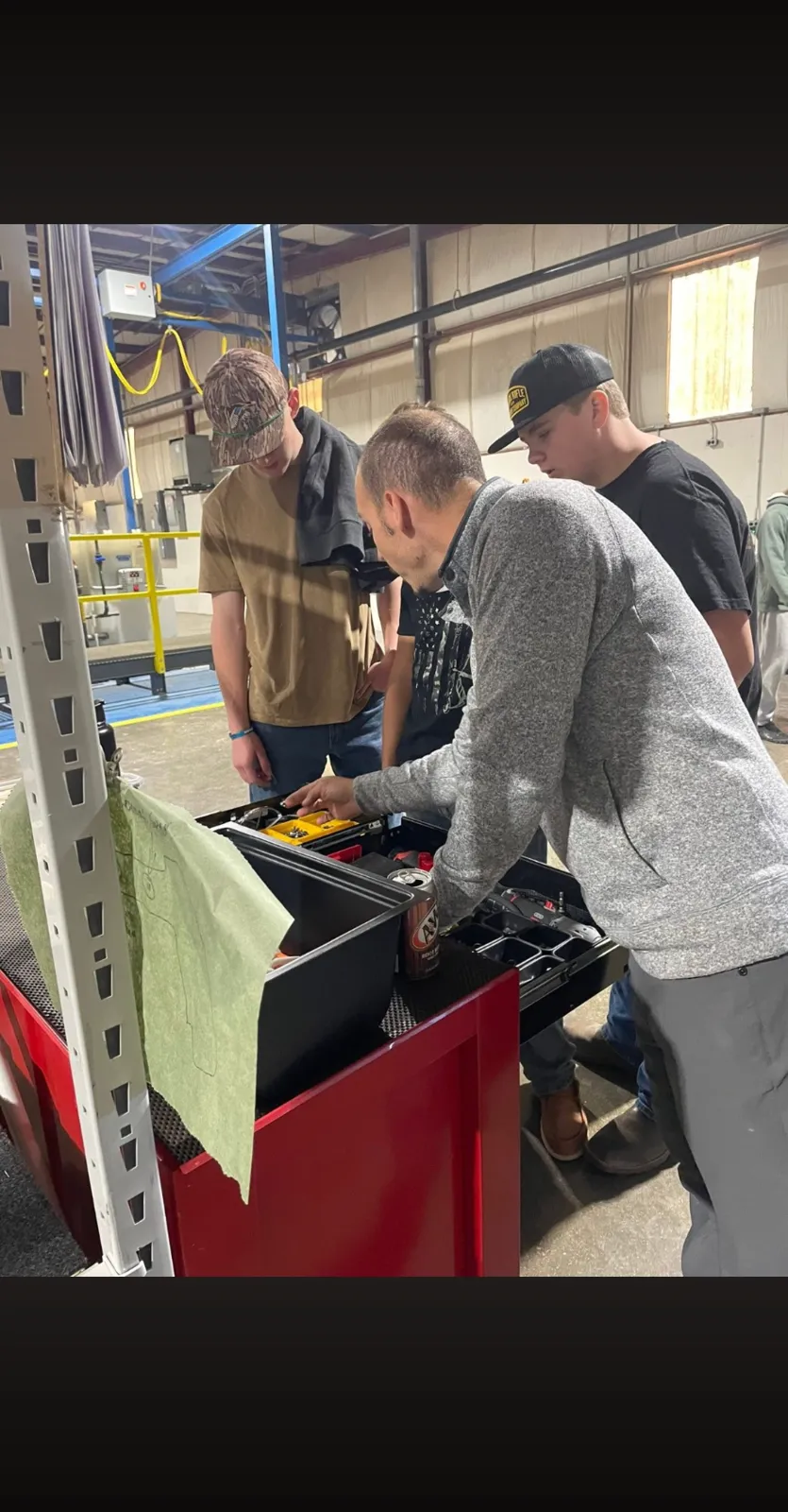 A mentor and students examining tooling during a workshop event at the AnoPRO plant