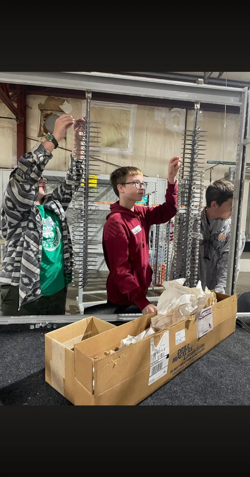 Students hanging small parts on anodizing racks during a plant event at AnoPRO