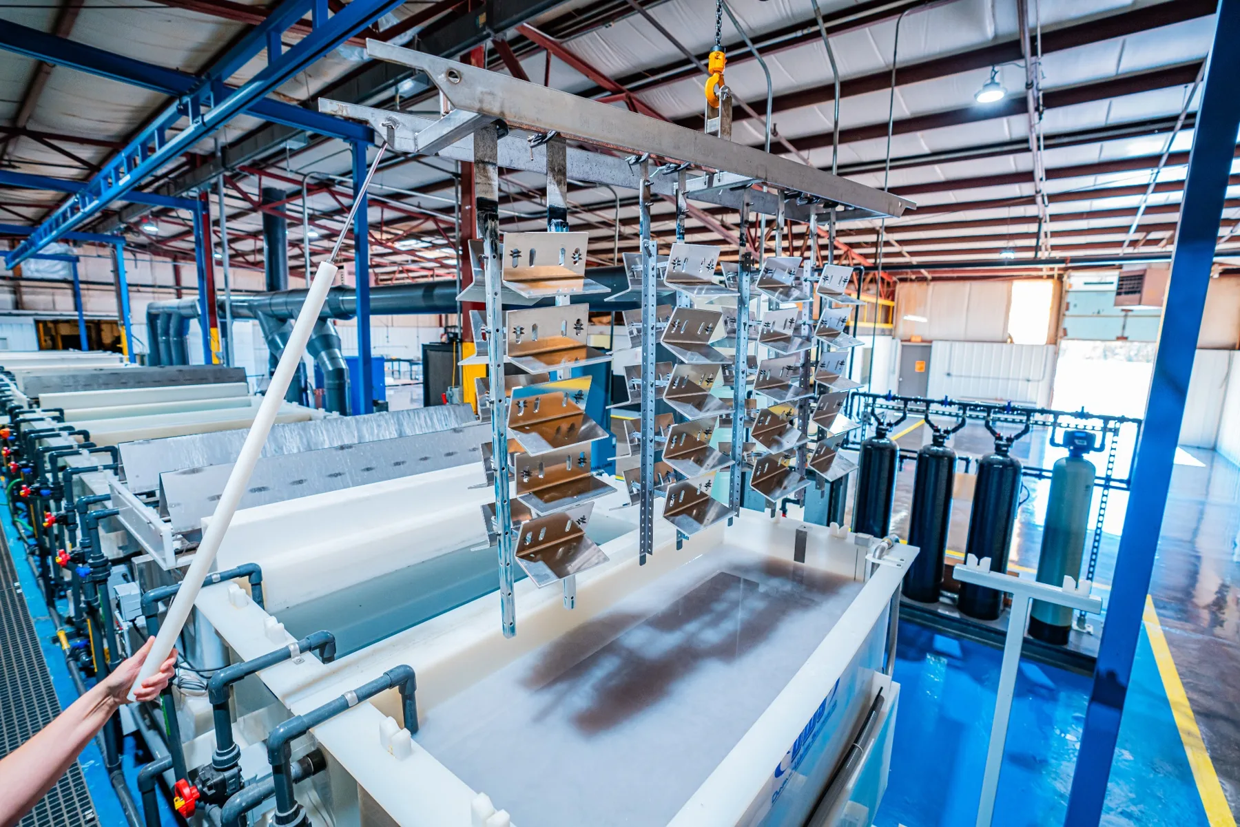 Racked aluminum parts over the anodizing line in the expanded AnoPRO facility in Paoli